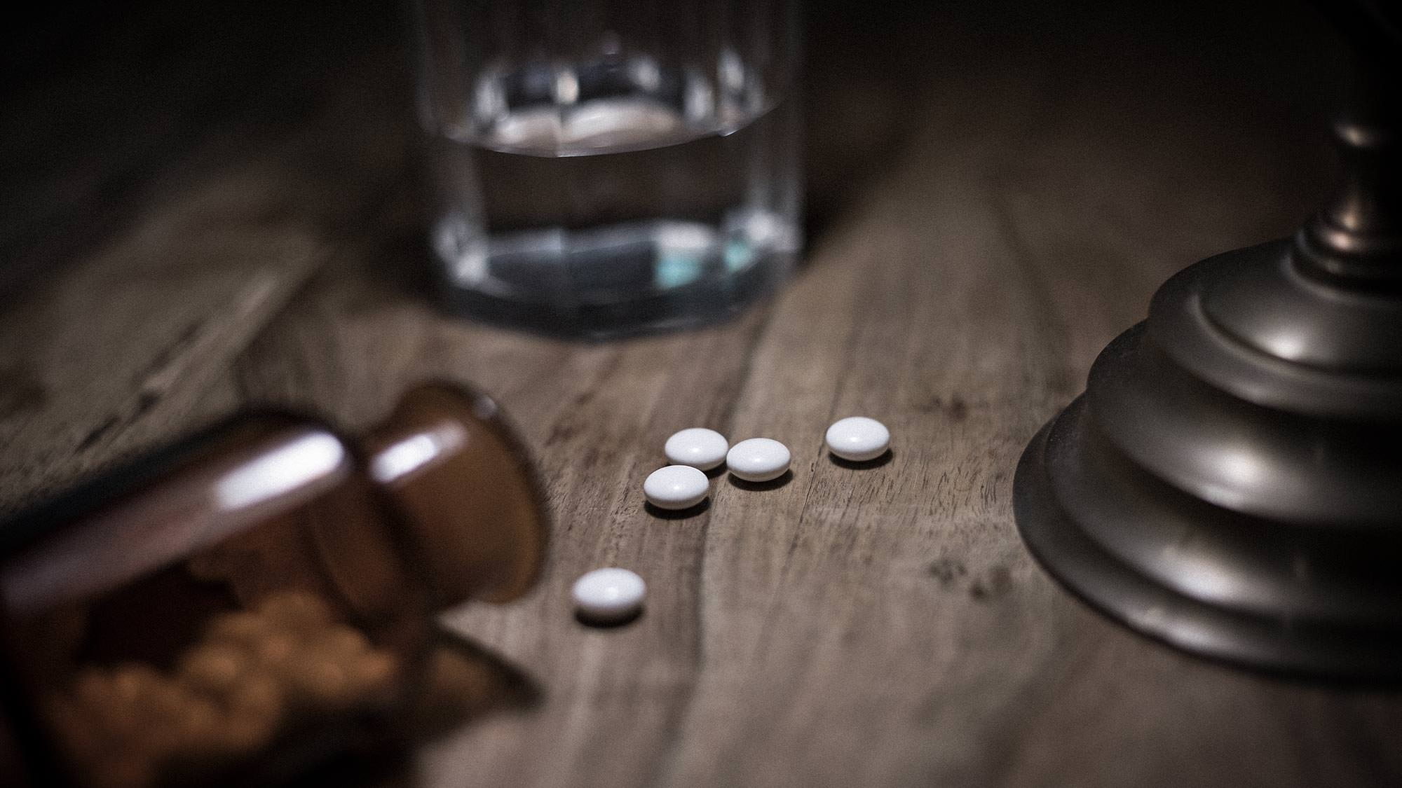 Tabletten und ein Wasserglas auf einem Tisch